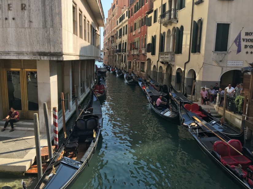 Gondolas parked on both sides of a small canal in Venice